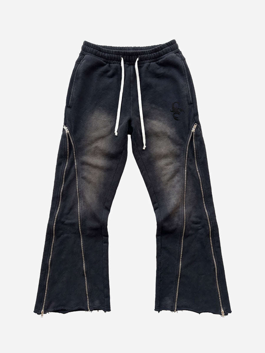 Black flared pants with long zipper tracks running down the lower legs