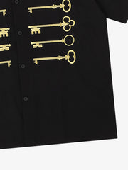 Camisa negra de algodón con botones y motivo de llave bordado en dorado.