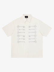 Camisa negra de algodón con botones y motivo de llave bordado en dorado.