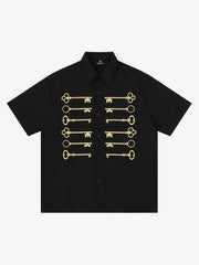 Camisa negra de algodón con botones y motivo de llave bordado en dorado.