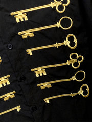 Camisa negra de algodón con botones y motivo de llave bordado en dorado.