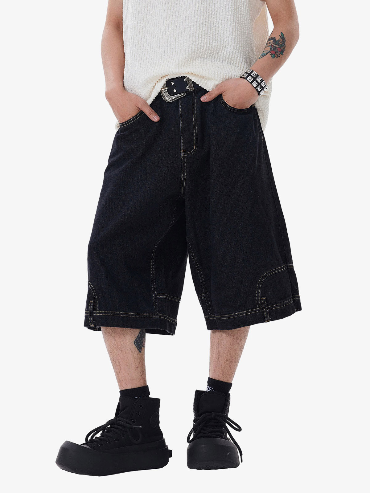 Person wearing black baggy shorts with a white top on a white background